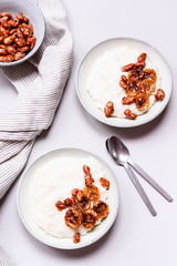 Creamy Rice Porridge or Pudding with caramelized bananas and nuts in bowls on grey concrete background. Selective focus