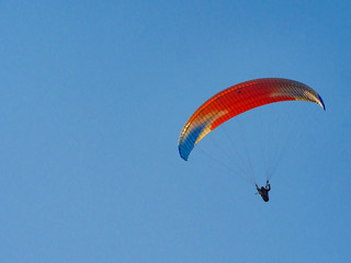 Paraglider flying in blue sky.