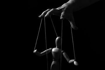 Conceptual image of a hand with strings to control a marionette in monochrome - 342245307