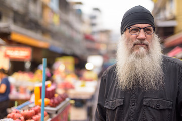 Face of mature bearded tourist man with eyeglasses thinking in Chinatown