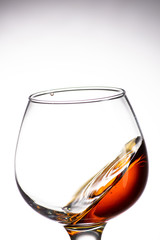 drop falling in a round glass with cognac or whiskey, a splash at an amazing angle