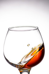drop falling in a round glass with cognac or whiskey, a splash at an amazing angle