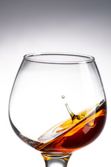 drop falling in a round glass with cognac or whiskey, a splash at an amazing angle