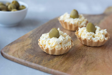 cheese snack with olives in baskets of dough on a wooden board