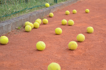 yellow tennis balls lying on the orange clay court after individual coaching