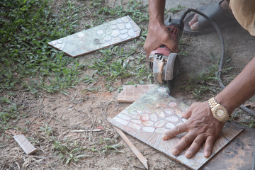 worker cutting a tile using an angle grinder at construction site