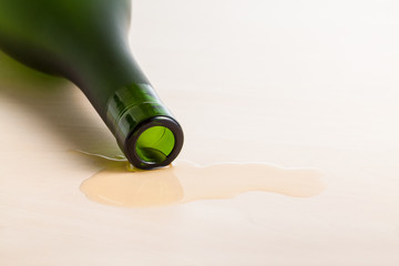 edge of cognac bottle in spilled liquid on table