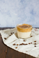 Obraz na płótnie Canvas Iced Dalgona Coffee with chocolate powder in a glass cup. Trendy fluffy creamy whipped coffee.