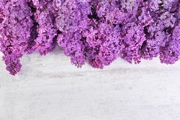 top view on purple lilac flower arrangement on white table with copy space at bottom