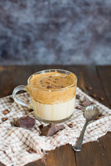 Iced Dalgona Coffee with chocolate powder in a glass cup. Trendy fluffy creamy whipped coffee.