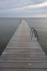 Obraz premium jetty in the ocean, no people. there is a ladder on the jetty. cloudy day