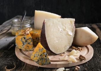 Pieces of Jugas and Shropshire Blue  cheese with grapes on a wooden plate at  background