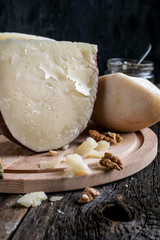 Pieces of Jugas and Shropshire Blue  cheese with grapes on a wooden plate at  background