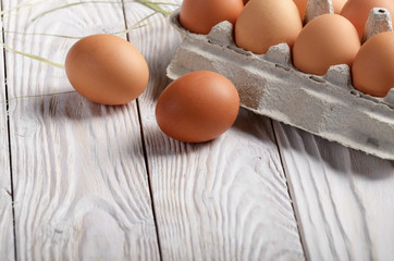 Raw organic brown chicken eggs in eco friendly paper carton on white kitchen wooden table