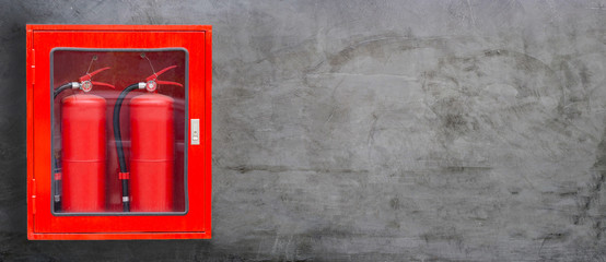 Fire Extinguisher in red cabinet on concrete wall background.