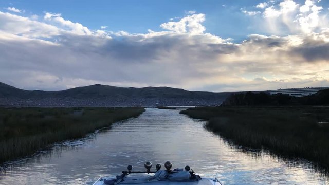 Tilt down shot of the boat sailing to Puno, Peru. Transition from a blue sky to a boat on the way to Puno. View of totorales in the water from a boat in Peru.