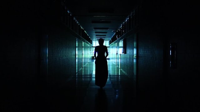 Abstract symmetrical interior reflective corridor backlit silhouette of a woman sashaying away