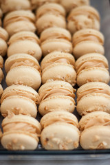Homemade french macaroons with brown shells, peanut butter cream and peanuts. Selective focus.