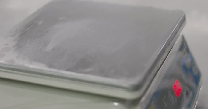 Weighing scale calibration in laboratory using a set of reference standard stainless steel knob cylindrical weights. White gloves and forceps. High standard of procedure for high accuracy.