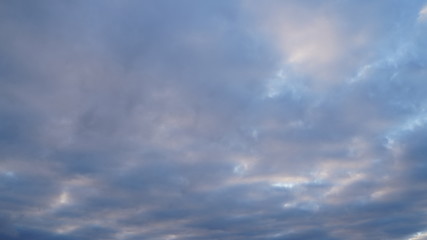 Obraz premium A beautiful evening blue sky at sunset with flaming bright light clouds. Warm evening.