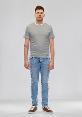 people concept - young man in striped t-shirt and jeans over grey background