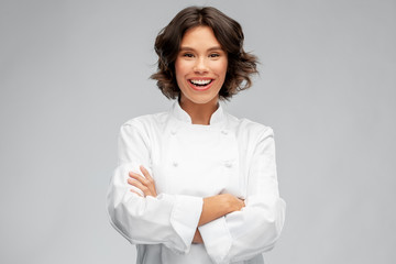 cooking, culinary and people concept - happy smiling female chef in toque over grey background