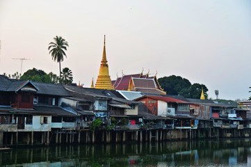 The Thai pagoda is surrounded by houses by the river.