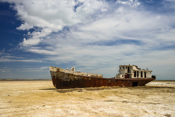 Fototapeta na wymiar Old fishing schooner at the bottom of the dried Aral Sea