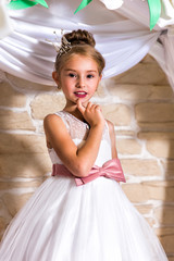 Portrait of girl dressed as bride with diamond diadem on the background of flower arch