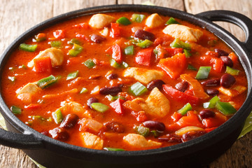 Mexican chicken with red beans in spicy chili sauce close-up in a pan. horizontal