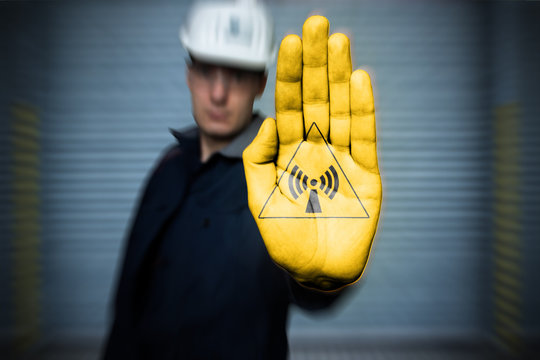 warning sign pictogram Warning of non-ionizing radiation (in german Warnzeichen, Warnung vor nicht ionisierender Strahlung) Painting on workers hand