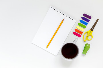 flatlay on a white background, stationery, notebook, pencil, stapler, scissors, stickers and a cup of tea or coffee 