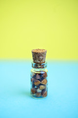Vertical picture with soft focus of tiny glass jar with buckwheat on blue and yellow background, side view. Concept of healthy nutrition, diet, vegetarian products. Empty space for text and design