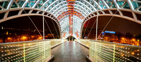 Panoramic image of architecture and pathway of iliuminated Peace bridge in Tblisi at night time. Georgia.25.03.2020. © Evaldas