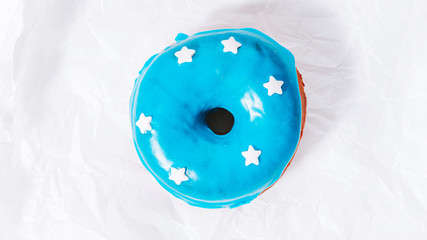 donut with blue icing and white stars on white paper