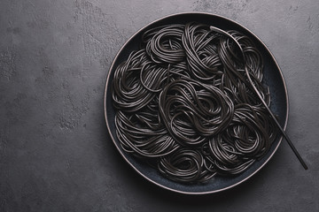 Squid Ink Pasta in bowl. Black Italian spaghetti on dark background