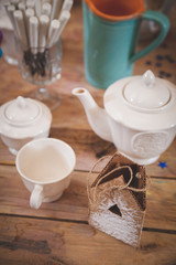 Fototapeta na wymiar An empty white tea cup for serving tea or coffee for breakfast and afternoon tea or a buffet table and a retreat. Large white teapot with tea and sugar bowl on a wooden table. Soft Selective Focus