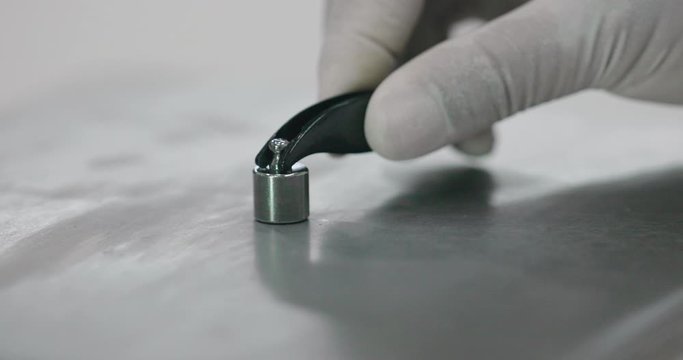 Close up of weighing scale calibration in using a set of reference standard stainless steel knob cylindrical weights. High standard of procedure for high level of precision of daily checks.