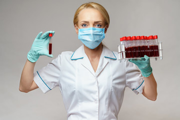 medical doctor nurse woman wearing protective mask and gloves - holding rack with virus blood tests
