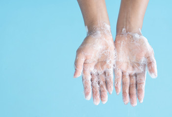Closeup woman's hand washing with soap on blue background, health care concept