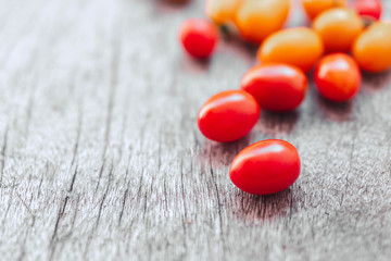 Red cherry tomatoes ceramic bowl on old wooden background, vintage tone