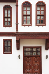 Old traditional Turkish wooden house has brown windows and door with white walls.