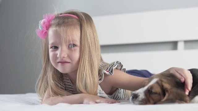 A cute little girl is in bed with a puppy.