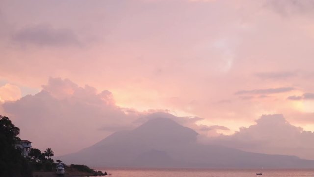 sunset at clear atitlan lake in guatemala - small boat in the middle of the lake at sunset between clouds, volcanoes and mountains with purple colors in the sky