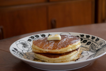 自宅のホットプレートで焼いたパンケーキ　仕上げに粉砂糖をふりかける様子