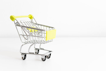 Shopping cart on white background. Small miniature shop trolley with space for your text. Copyspace mock up banner