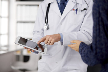 Male doctor using tablet computer in clinic, close-up. Perfect medical service in hospital. Medicine and healthcare concept