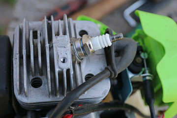 Engine of gasoline trimmer. Spark plug in engine head.