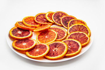 Fototapeta na wymiar Sicilian sliced ​​orange on a white plate on a white background. Sliced ripe Sicilian oranges against background. Healthy and tasty red sliced ​​orange