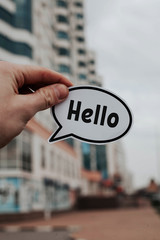 a man's hand holds a piece of paper with the inscription Hello